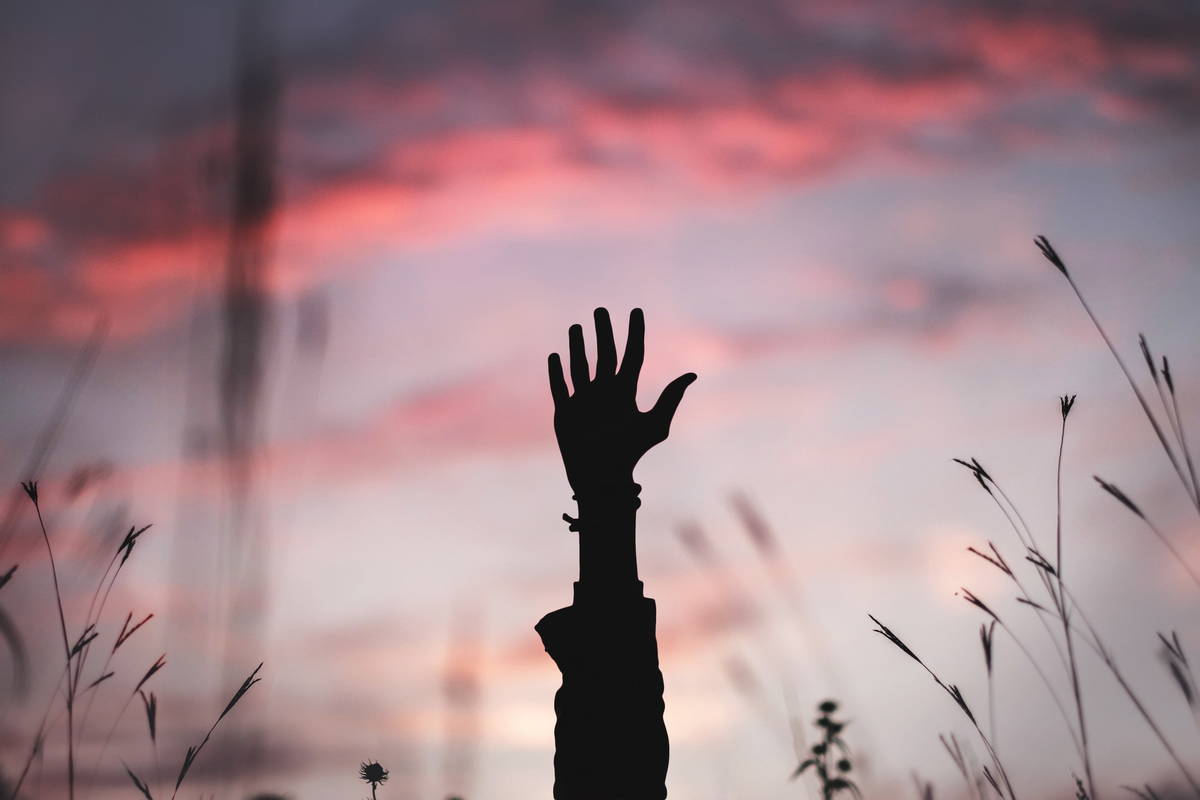 bryan-minear-ywavtqgnyji-unsplash.jpg Abendstimmung und eine unscharfe Hand wird in den Himmel gestreckt.