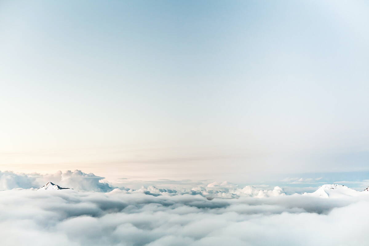 Ein paar Bergspitzen ragen über das Wolkenmeer hinaus. Oberhalb ist blauer Himmel.